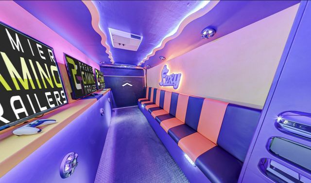 Interior of a Mini Adventurer gaming theater, owner-branded with a lit Foxy sign above coral and purple bench seating